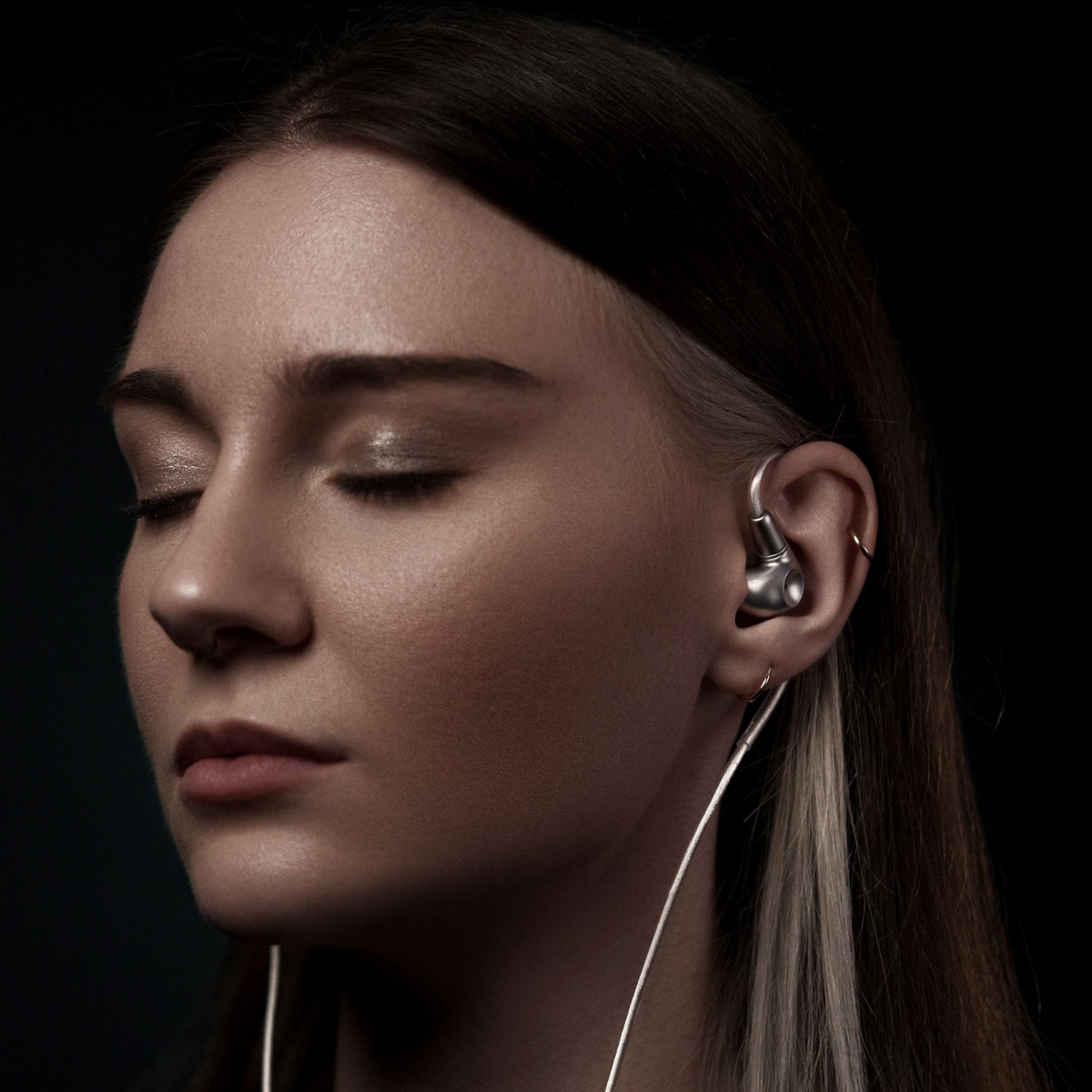 Frau mit Meze Audio Astru Kopfhörern in den Ohren und mit geschlossenen Augen die Musik genießt.